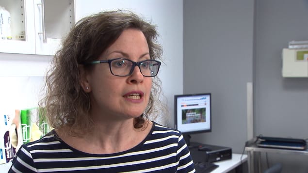 Mélanie Henderson porte des lunettes et accorde une entrevue dans son bureau.