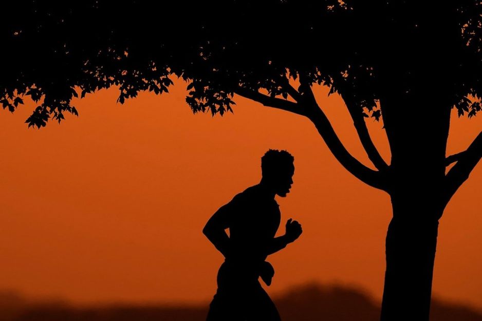 文件照片 - 一名男子在热夏的日落时分,在堪萨斯城的公园慢跑,背影映衬在天空中,2022年8月1日。 (美联社照片/查理·里德尔,文件)